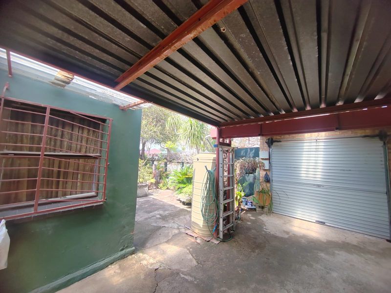 Covered outdoor patio area featuring a corrugated metal roof, concrete flooring, and direct access to a roller garage door.