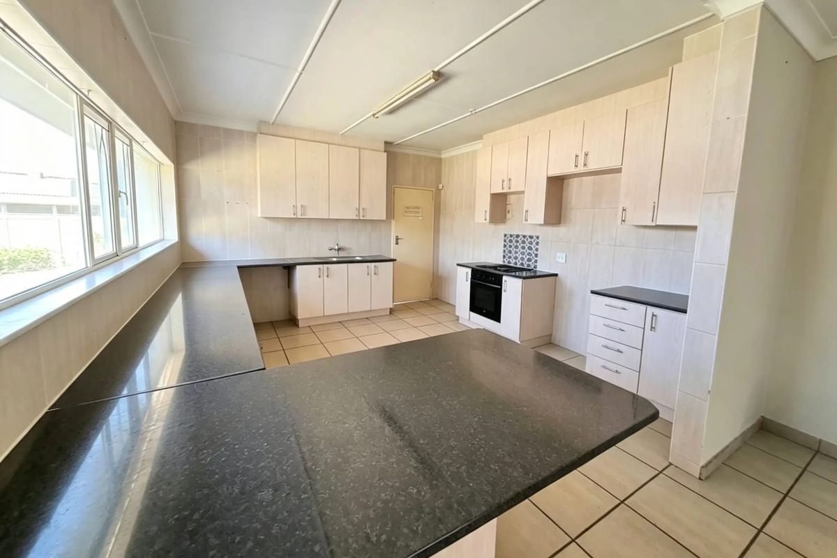 Spacious kitchen featuring ample built-in cabinetry, granite countertops, integrated oven and hob, and tiled flooring throughout.