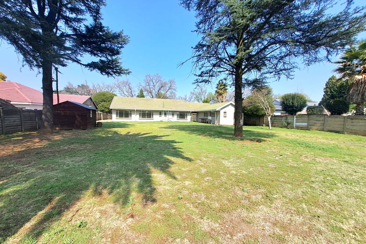 Spacious rear garden featuring a large lawn, mature trees, and a precast concrete boundary wall, providing a private outdoor area for the property.