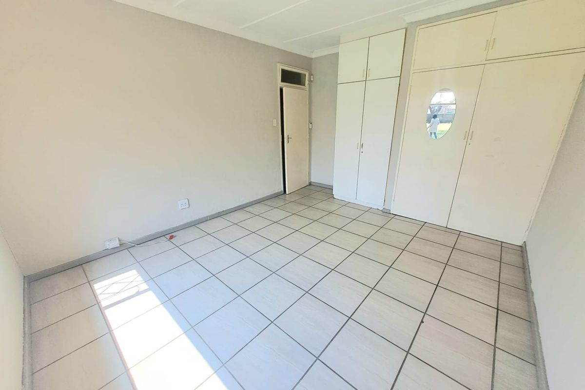A vacant bedroom featuring neutral tiled flooring and ample built-in cupboard storage, offering a clean canvas for personalization.