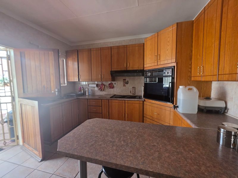 A functional kitchen featuring traditional wooden cabinetry, built-in oven, hob, extractor fan, and a breakfast bar, with direct access to the exterior via a stable door.