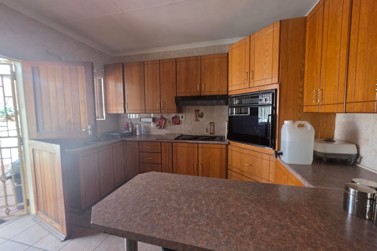 A functional kitchen featuring traditional wooden cabinetry, built-in oven, hob, extractor fan, and a breakfast bar, with direct access to the exterior via a stable door.
