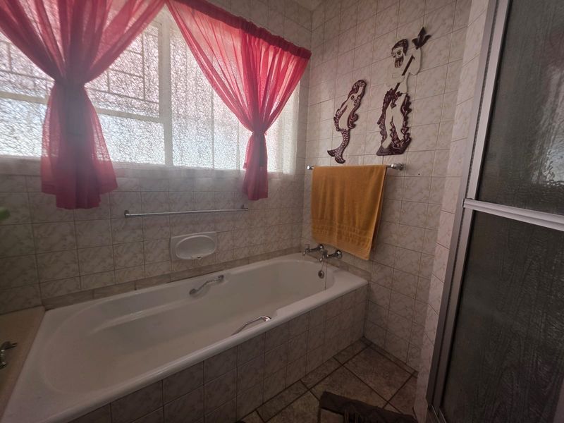 Bathroom featuring a built-in bathtub, separate shower enclosure, and full-height ceramic wall tiling.