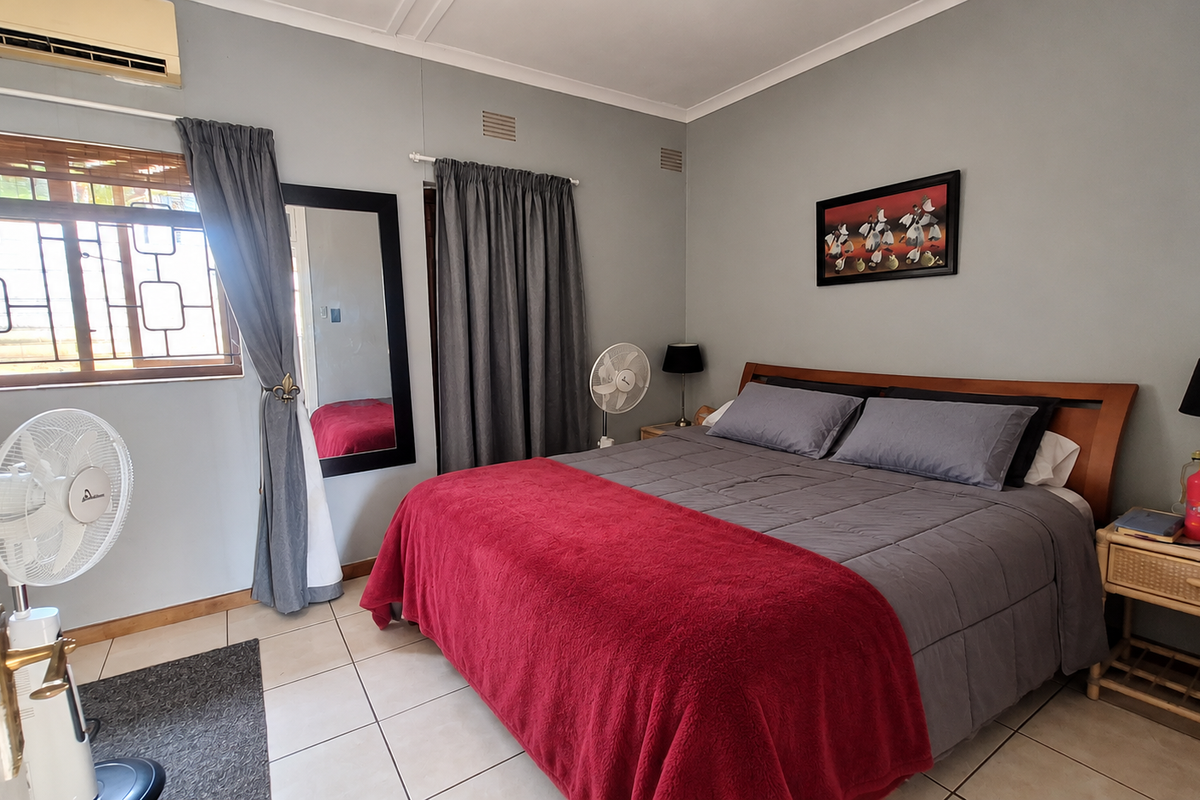 A bedroom featuring tiled flooring, an air conditioning unit, and security bars on the window.