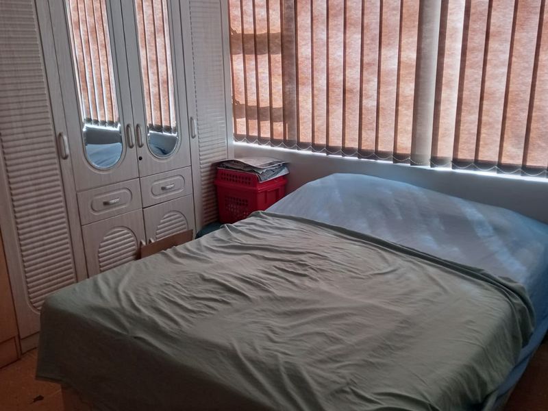 A bedroom featuring a built-in wardrobe with mirrored panels and vertical window blinds.