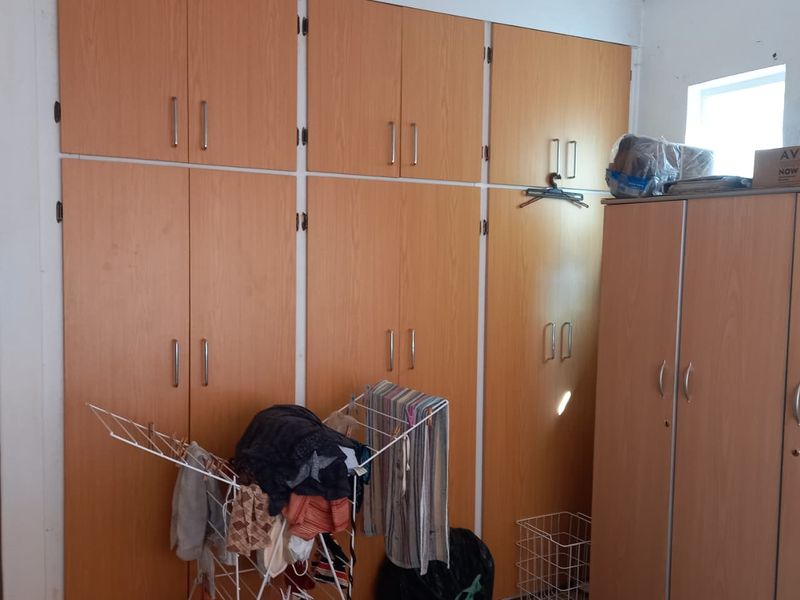 Bedroom featuring extensive floor-to-ceiling built-in wooden cabinetry and wardrobes providing ample storage space.