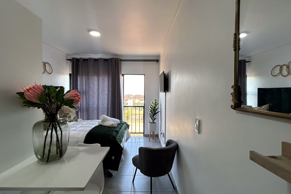 A well-lit bedroom featuring tiled flooring, recessed lighting, and direct access to a private balcony.