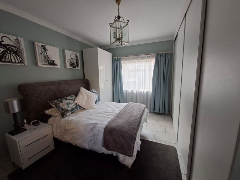 A well-maintained bedroom featuring built-in wardrobes, tiled flooring, and neutral wall tones, offering a comfortable and functional living space.