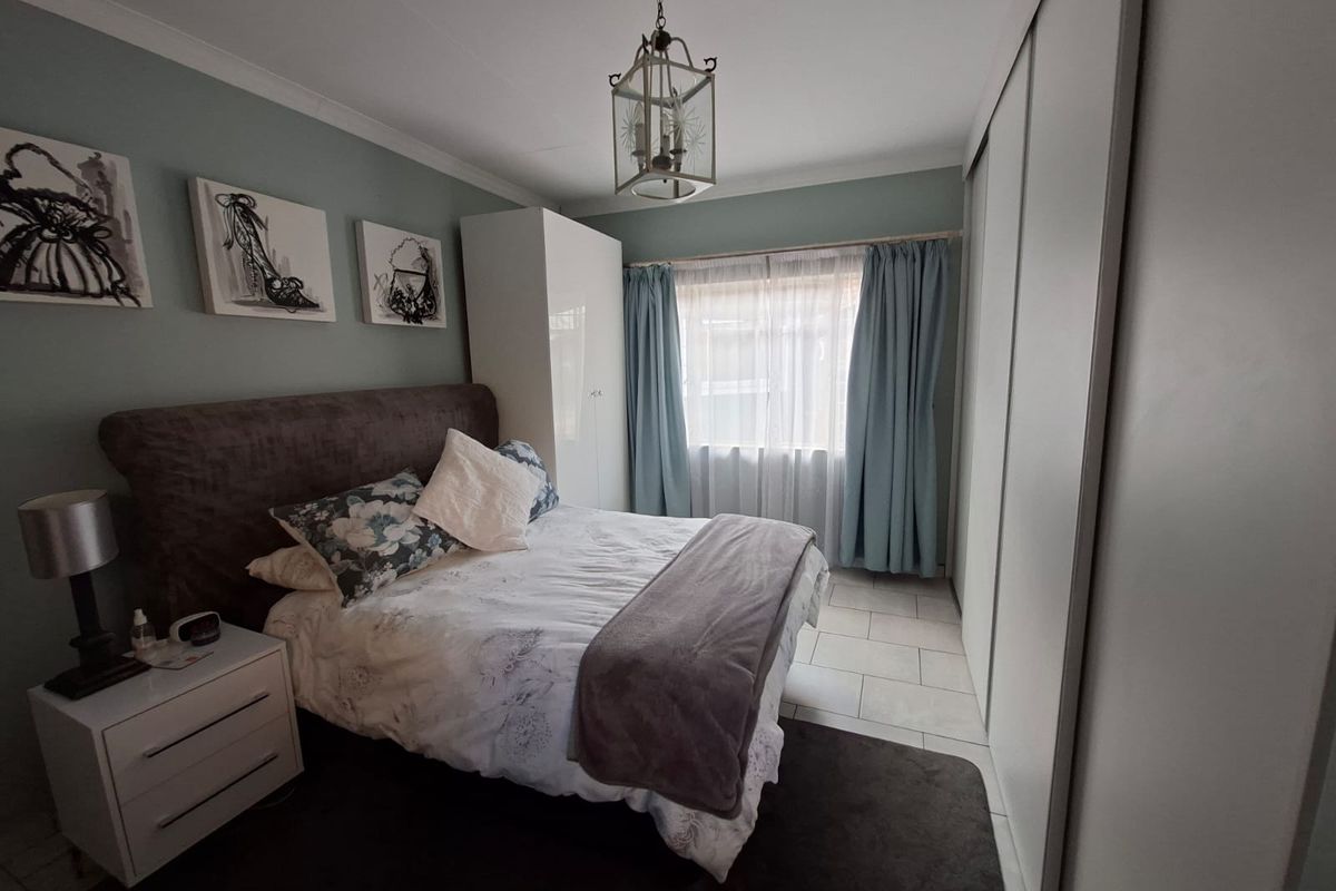 A well-maintained bedroom featuring built-in wardrobes, tiled flooring, and neutral wall tones, offering a comfortable and functional living space.