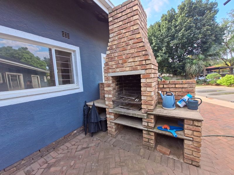 Outdoor patio area featuring a built-in brick braai and paved flooring, providing a functional space for outdoor cooking and entertainment.
