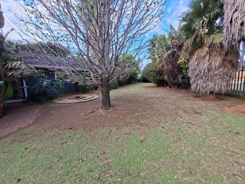 Spacious rear garden featuring mature trees, a paved circular feature, and established perimeter landscaping.