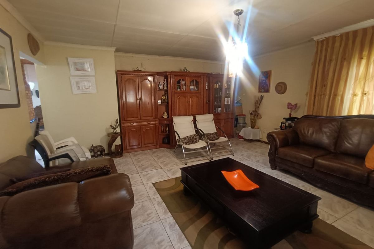 A living room featuring tiled flooring and a central pendant light fixture, with visible wear on the ceiling tiles.