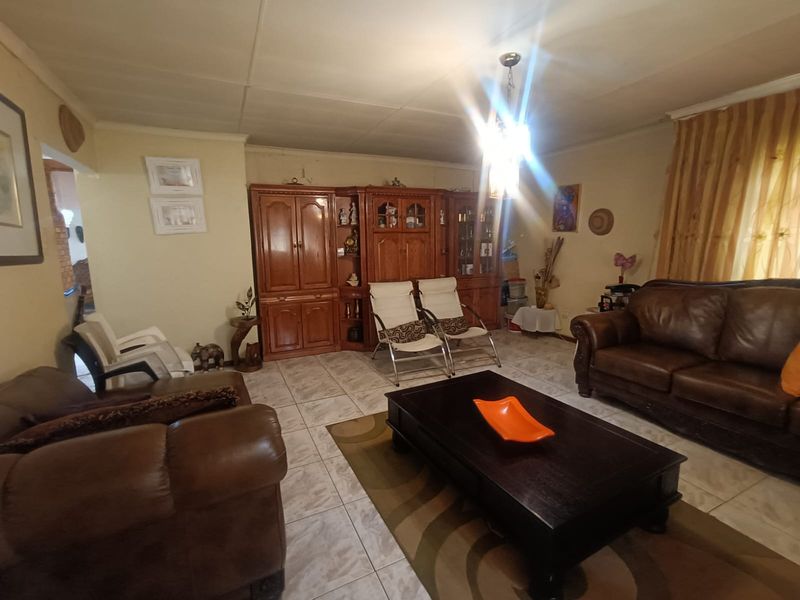 A living room featuring tiled flooring and a central pendant light fixture, with visible wear on the ceiling tiles.