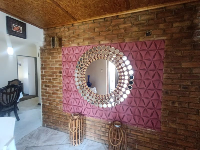 Entrance area featuring an exposed brick wall with decorative textured paneling and tiled flooring.