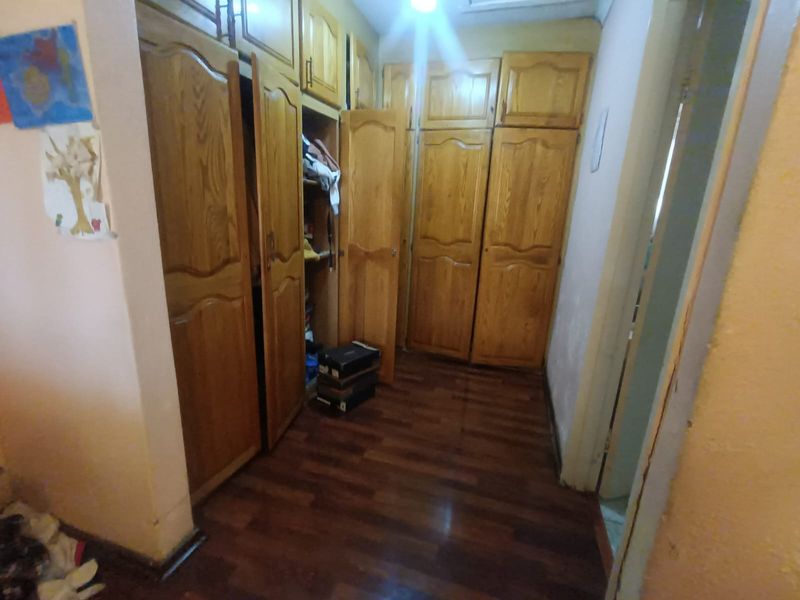 A bedroom featuring extensive built-in wooden cabinetry and dark laminate flooring, offering ample storage space.