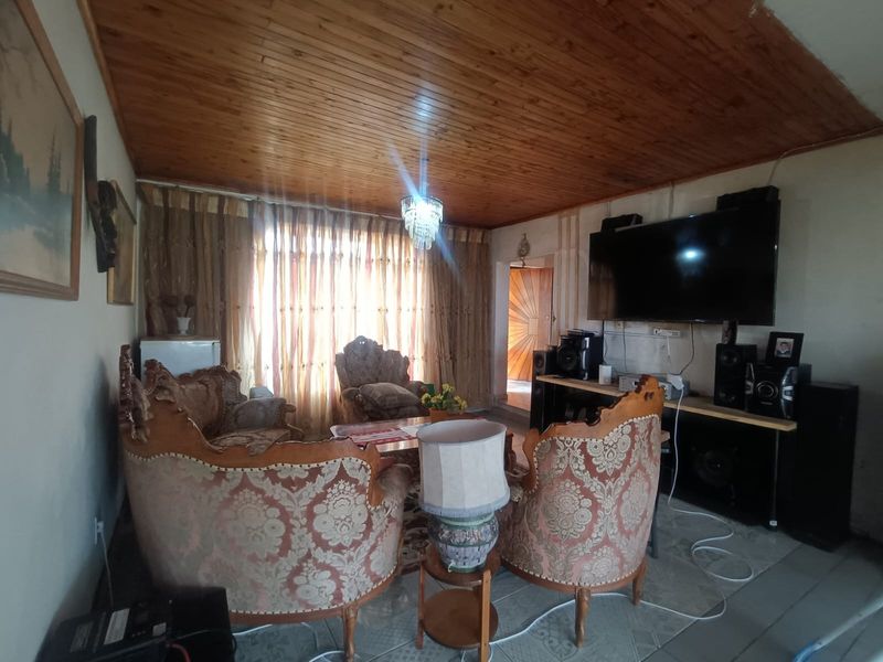 A living room featuring a timber tongue and groove ceiling and tiled flooring, requiring cosmetic updates to improve the overall aesthetic.
