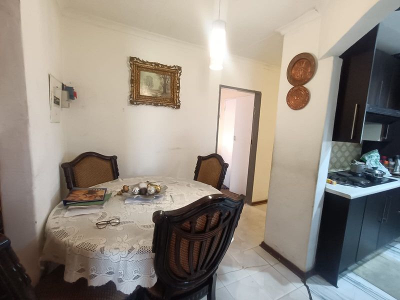 Open plan dining area adjacent to a compact kitchen featuring dark cabinetry and tiled flooring.