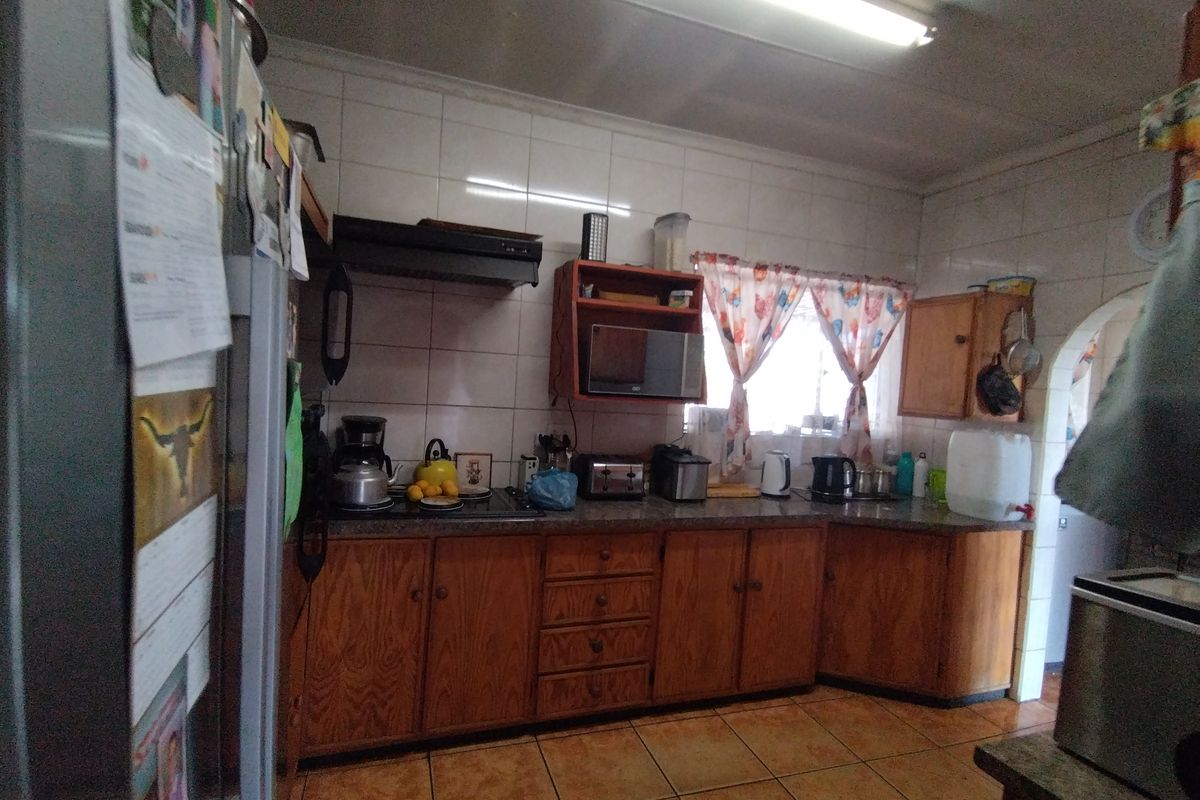 A functional kitchen featuring wooden cabinetry, tiled backsplash, and tiled flooring, equipped with a built-in stove and extractor fan.