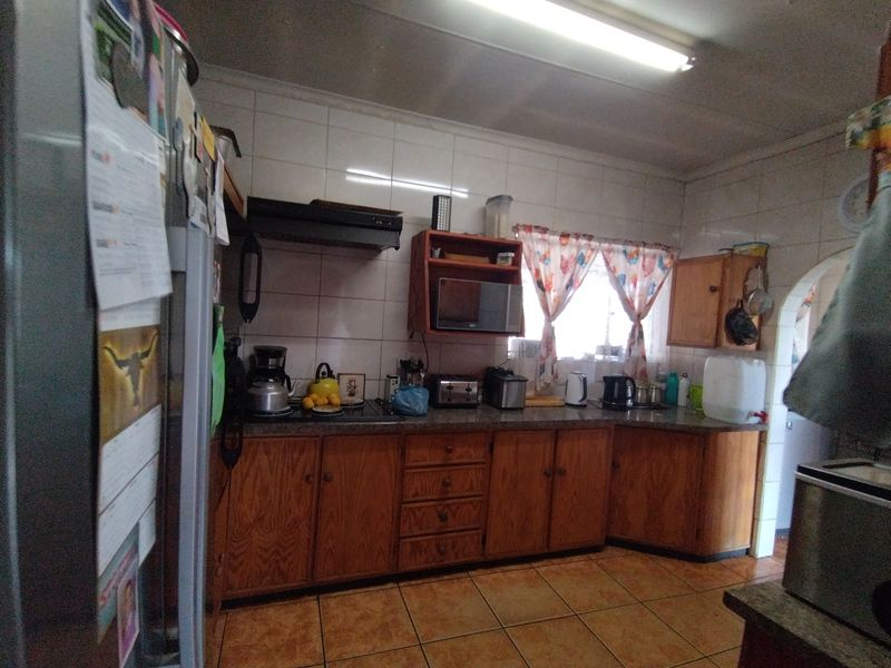 A functional kitchen featuring wooden cabinetry, tiled backsplash, and tiled flooring, equipped with a built-in stove and extractor fan.