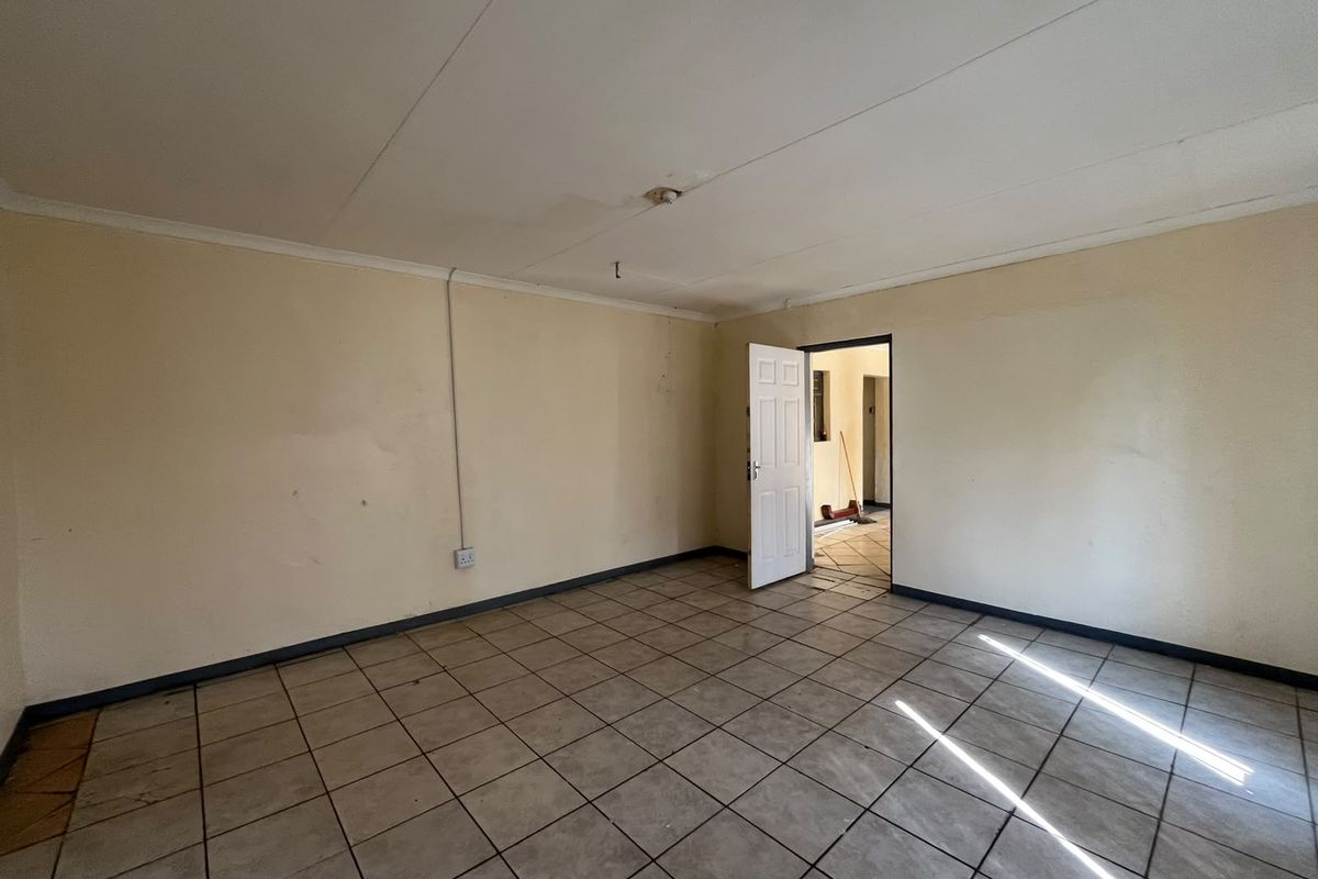 An empty living room featuring ceramic tiled flooring, neutral walls, and a standard internal door leading to an adjacent space.
