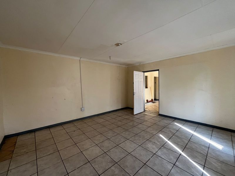 An empty living room featuring ceramic tiled flooring, neutral walls, and a standard internal door leading to an adjacent space.