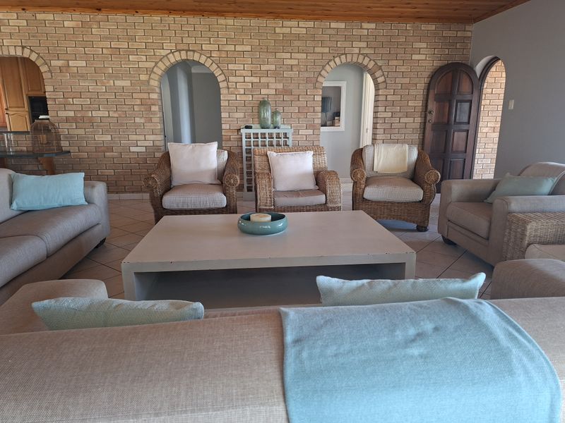 Spacious living room featuring a prominent exposed brick wall, arched architectural details, and a warm timber ceiling with neutral floor tiling.