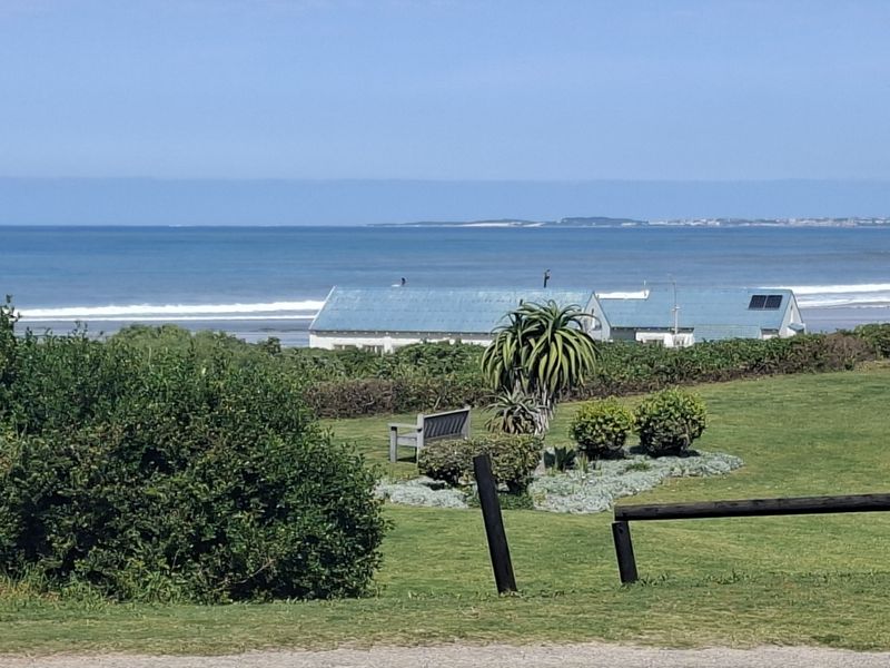 A scenic view overlooking a well-maintained garden with coastal landscape and ocean horizon in the background.