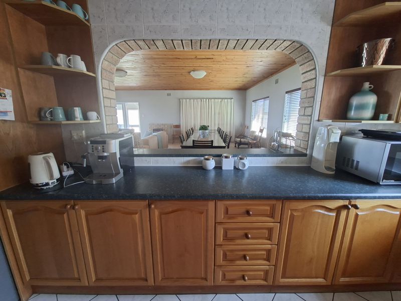 Kitchen featuring timber cabinetry, laminate countertops, and a distinctive brick archway providing an open view into the adjacent dining and living area.