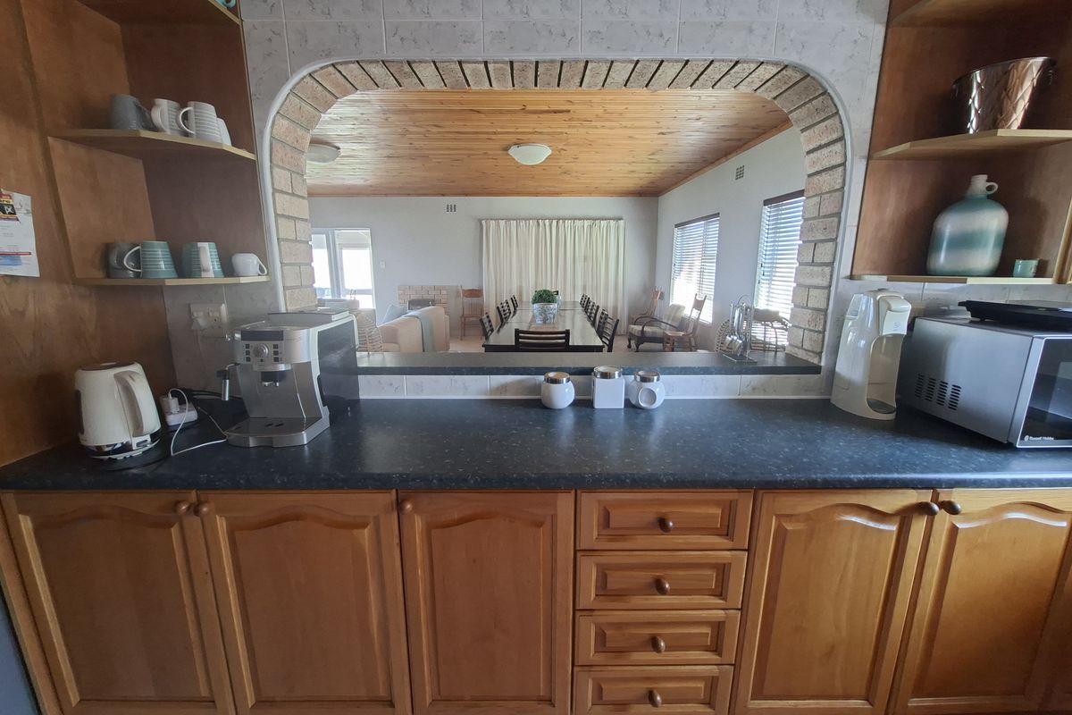Kitchen featuring timber cabinetry, laminate countertops, and a distinctive brick archway providing an open view into the adjacent dining and living area.