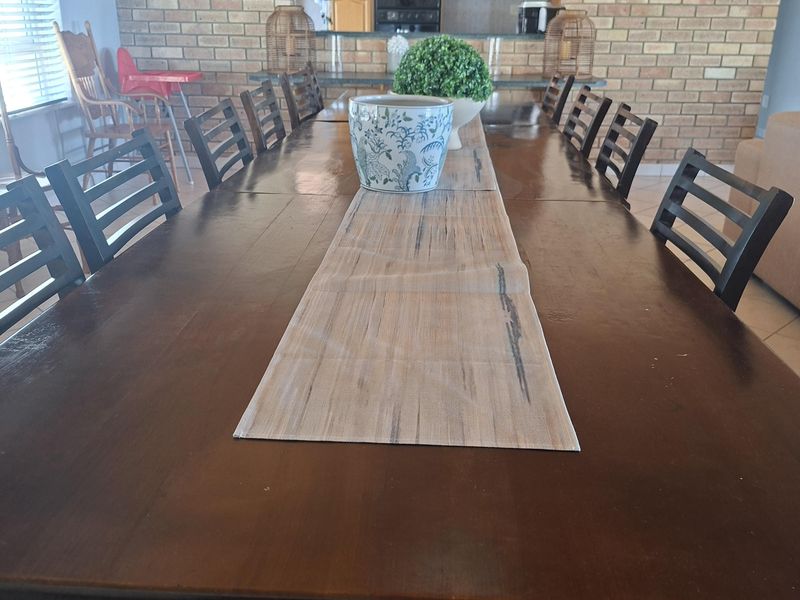 Spacious dining area featuring an exposed brick wall with an arched opening leading into the kitchen, complemented by tiled flooring and natural light.