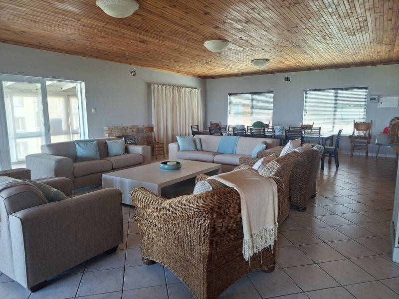 Spacious open-plan living and dining area featuring a warm timber ceiling, tiled floors, and a brick fireplace, offering a comfortable and inviting atmosphere.
