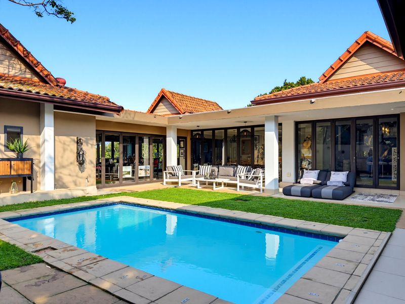 A well-maintained outdoor pool area featuring a swimming pool with tiled surround, covered patio space, and direct access to the home via bi-fold doors.