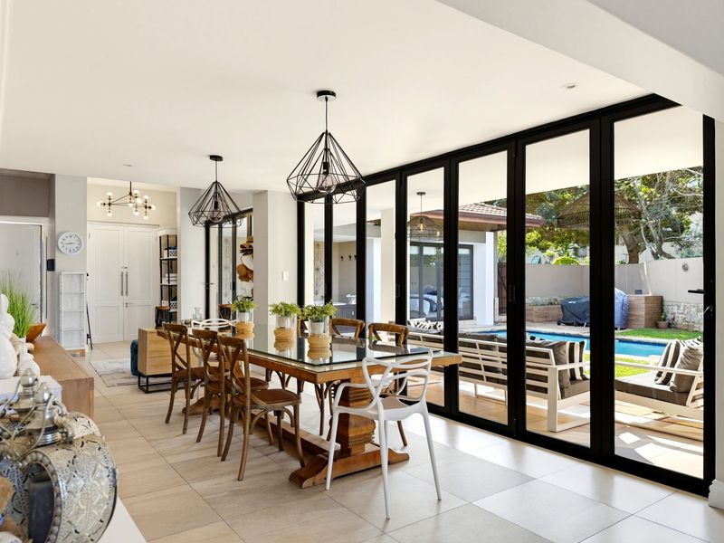 Spacious open-plan dining area featuring large black aluminium stacker doors that provide seamless indoor-outdoor flow to the pool area and patio.