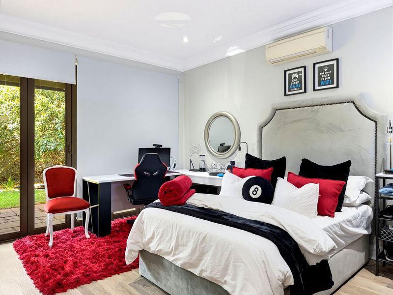 A well-maintained bedroom featuring a split-system air conditioner, recessed lighting, and direct access to the garden through a sliding glass door.
