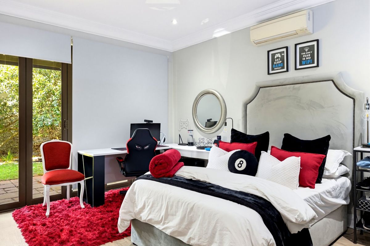A well-maintained bedroom featuring a split-system air conditioner, recessed lighting, and direct access to the garden through a sliding glass door.