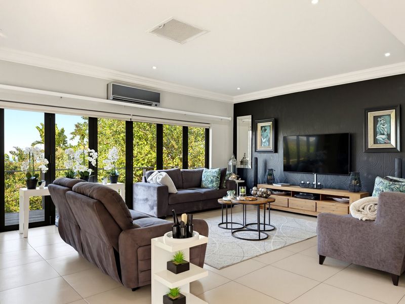 Spacious living room featuring large sliding glass doors, tiled flooring, recessed lighting, and a wall-mounted air conditioning unit.