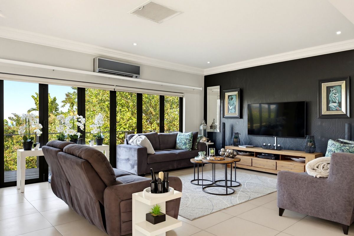Spacious living room featuring large sliding glass doors, tiled flooring, recessed lighting, and a wall-mounted air conditioning unit.