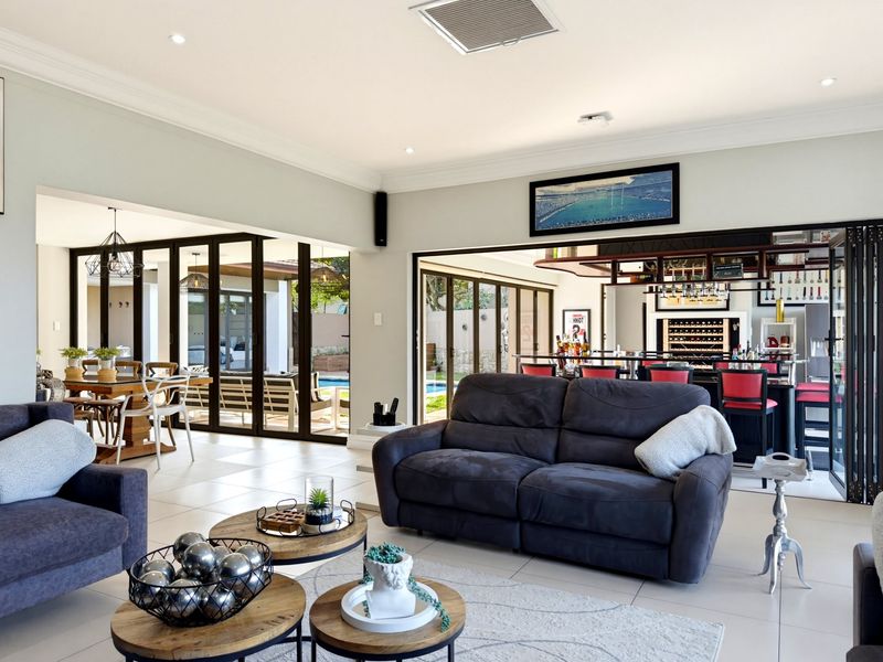 Spacious open-plan living area featuring tiled floors, ducted air conditioning, and seamless indoor-outdoor flow through bi-fold doors to the patio and bar area.