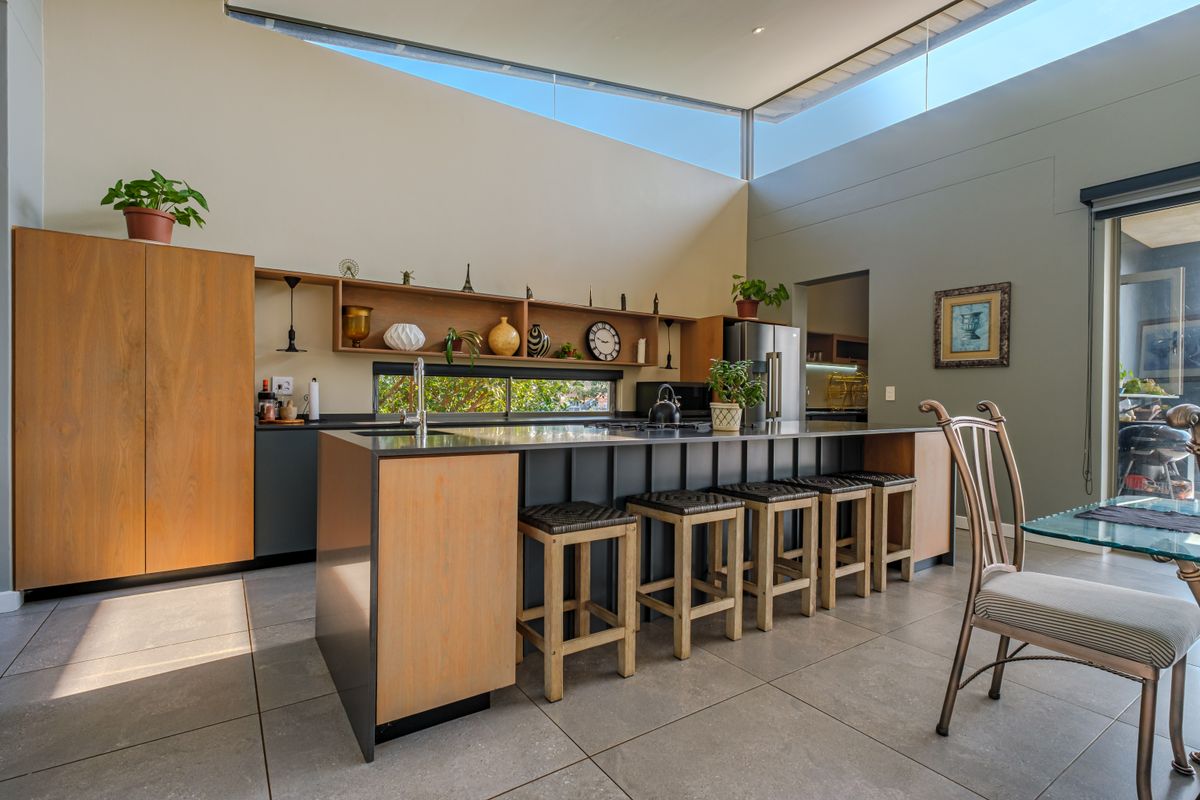 Modern kitchen featuring a large island with stone countertops, sleek cabinetry, and high clerestory windows that provide abundant natural light.