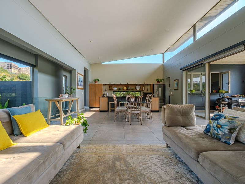 Spacious open-plan living and dining area featuring high ceilings with clerestory windows, modern kitchen cabinetry, and seamless flow to the outdoor patio.