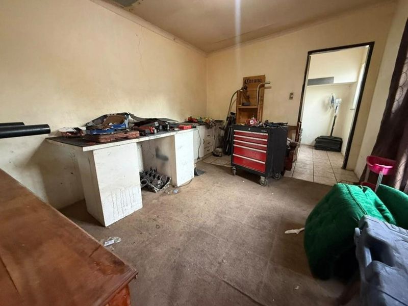 A utility or workshop space featuring a built-in workbench and tiled flooring, currently used for storage and maintenance tasks.