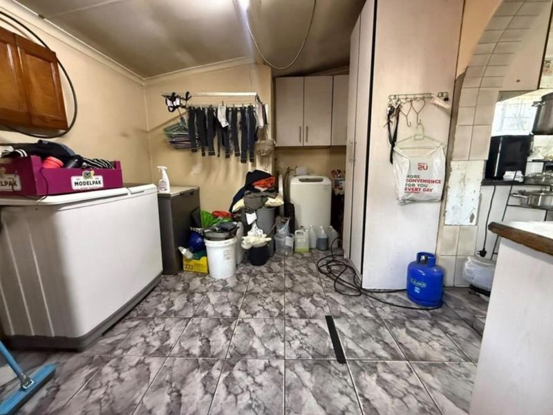 A functional laundry area featuring tiled flooring and built-in cabinetry, currently requiring cosmetic updates and maintenance to the walls and ceiling.