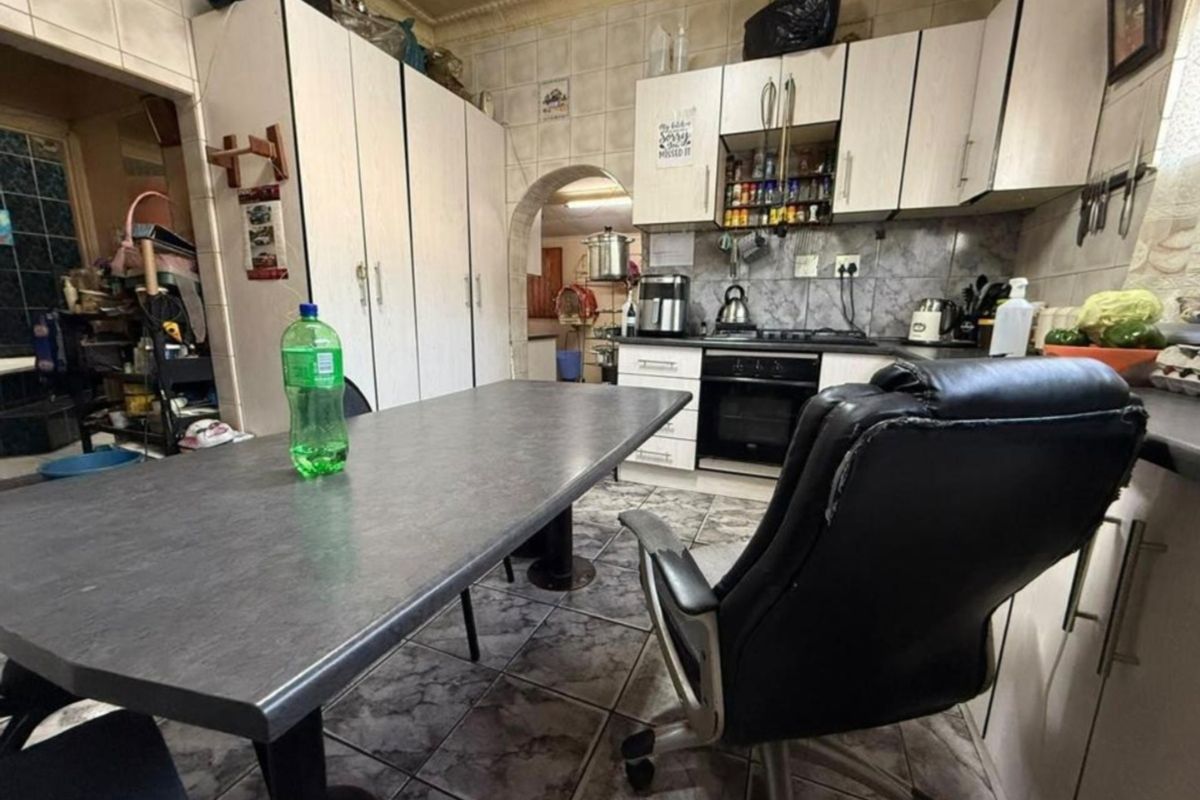 A functional kitchen featuring built-in cabinetry, a gas hob, and an oven, with tiled flooring and an arched entryway leading to adjacent spaces.