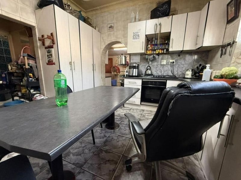 A functional kitchen featuring built-in cabinetry, a gas hob, and an oven, with tiled flooring and an arched entryway leading to adjacent spaces.