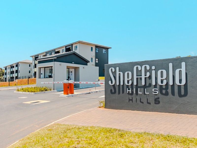 The entrance to Sheffield Hills apartment complex featuring a secure boom gate, guard house, and clear signage.