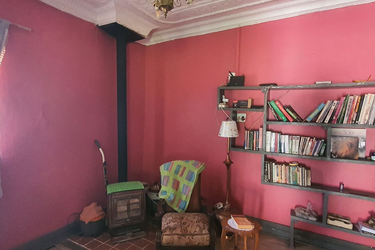 Living room featuring a cast iron fireplace, tiled hearth, ornate ceiling cornice, and built-in wall shelving.