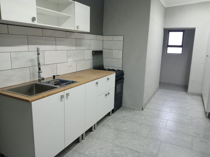 A clean, modern kitchen featuring white cabinetry, a wooden countertop, subway tile backsplash, and tiled flooring, presenting a functional and well-maintained space.