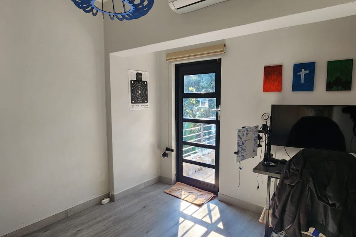 A bedroom featuring laminate flooring, an air conditioning unit, and a glass-panelled door providing access to an outdoor area.