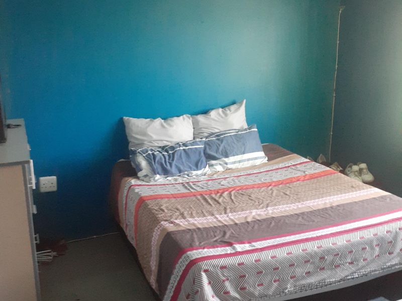 A bedroom featuring blue painted walls and standard electrical fixtures, requiring cosmetic updates to improve the overall aesthetic and finish.