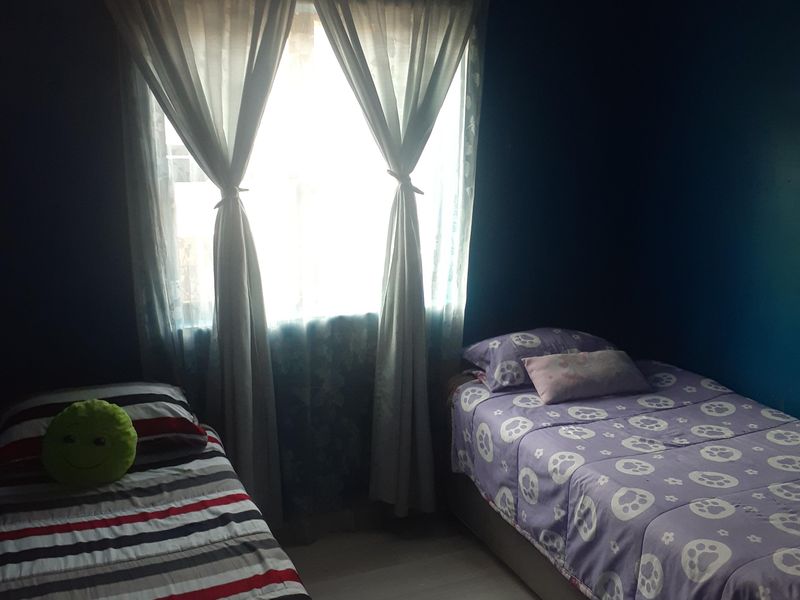 A bedroom featuring dark painted walls, laminate flooring, and a window with curtains.